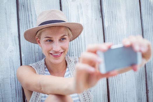 Pretty blonde woman taking selfie on wooden background