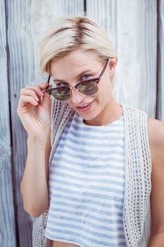 Pretty blonde woman smiling at the camera on wooden background