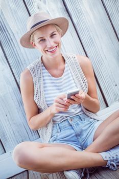 Pretty blonde woman texting with her mobile phone on wooden background 