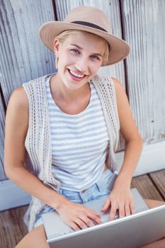 Pretty blonde woman using her laptop on wooden background