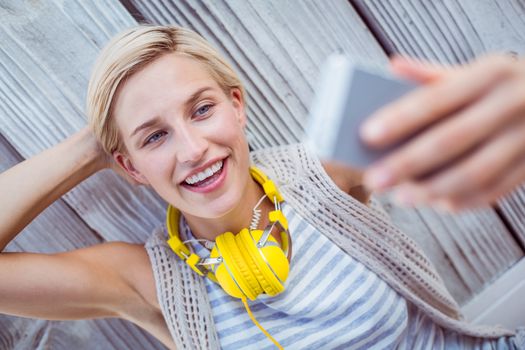 Pretty blonde woman taking selfie on wooden background