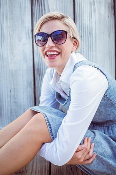 Pretty blonde woman wearing sun glasses on wooden background 