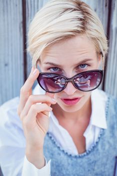 Pretty blonde woman wearing sun glasses on wooden background 
