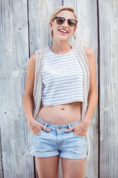 Pretty blonde woman standing hands in the pockets on wooden background