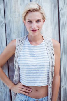 Pretty blonde woman smiling at the camera on wooden background