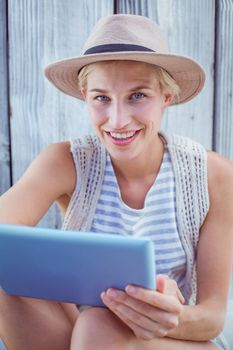 Pretty blonde woman using her tablet on wooden background