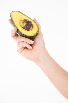 Woman holding half of an avocado on white background 