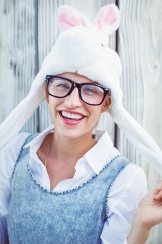 Pretty blonde woman smiling at the camera wearing funny hat on wooden background