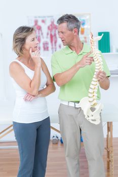 Doctor showing anatomical spine in medical office