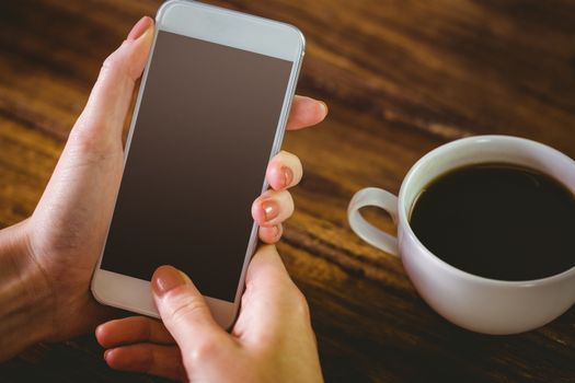 Woman using her smartphone on wooden table