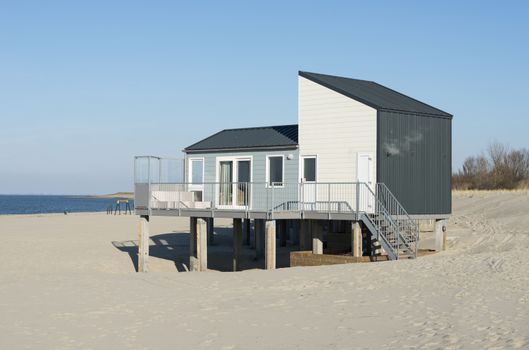 wooden beach nhouse for vacation on the sand near the blue water sea in holland with the dunes as background
