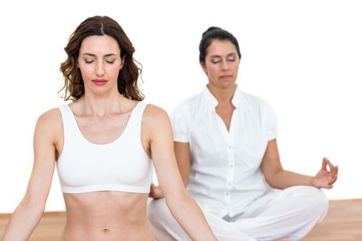 Women sitting in lotus pose on white background