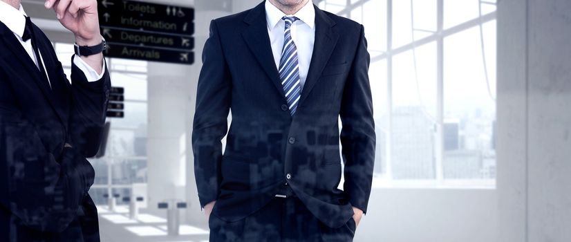 Smiling businessman standing with hands in pockets against airport terminal