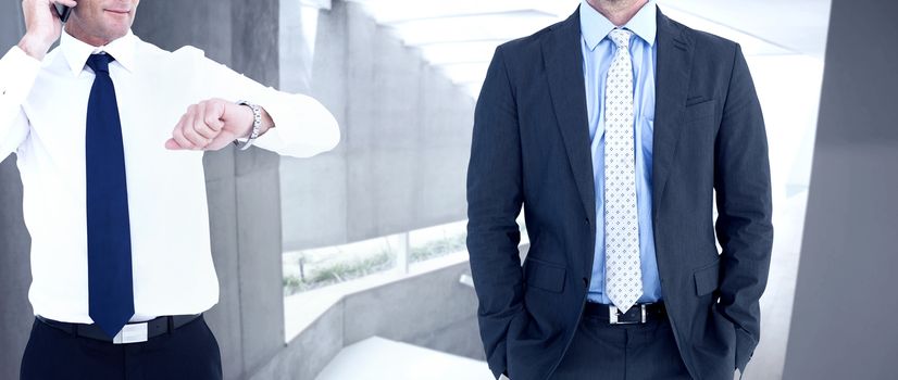 Businessman on the phone looking at his wrist watch against stylish modern home interior with staircase