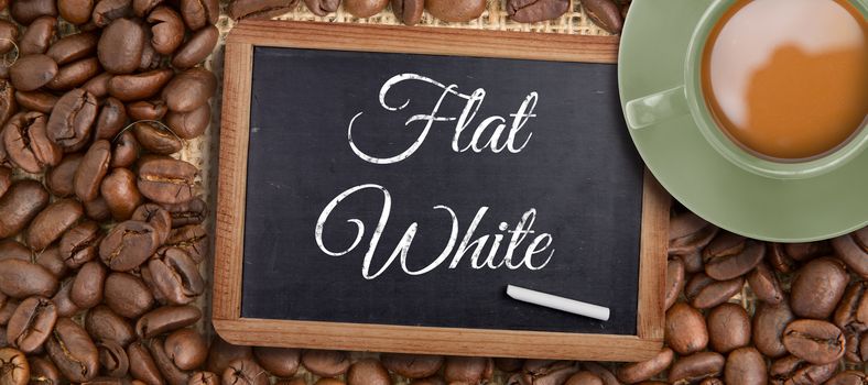 Green cup of coffee against chalkboard with piece of chalk