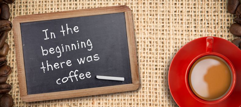 Red cup of coffee against chalkboard with piece of chalk