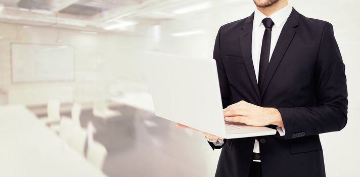 Mid section of a businessman using laptop against classroom