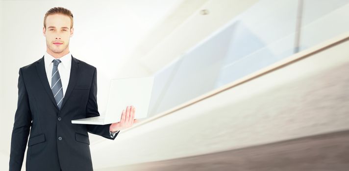 Serious businessman posing and holding laptop against modern home with large windows