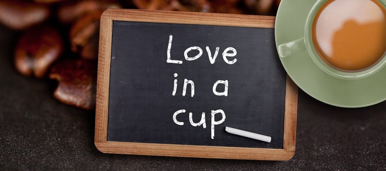Green cup of coffee against chalkboard with piece of chalk