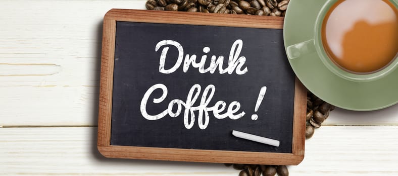 Green cup of coffee against chalkboard with piece of chalk