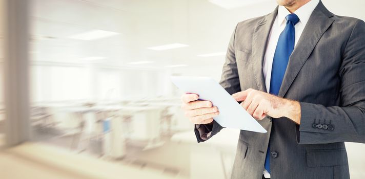 Businessman using his tablet pc  against empty class room