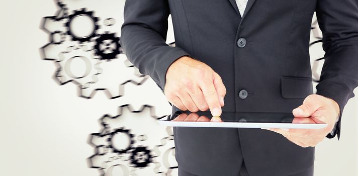 Businessman using his tablet pc  against turning cogs