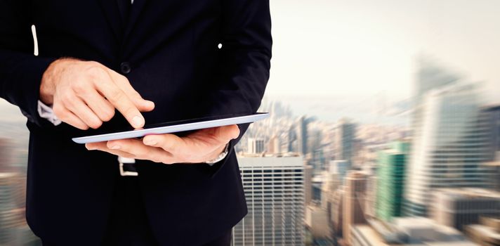 Mid section of a businessman touching digital tablet against new york