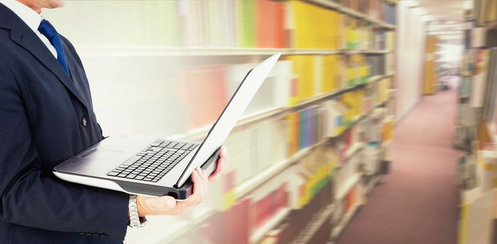 Businessman with watch using tablet pc against rows of bookshelves in the library