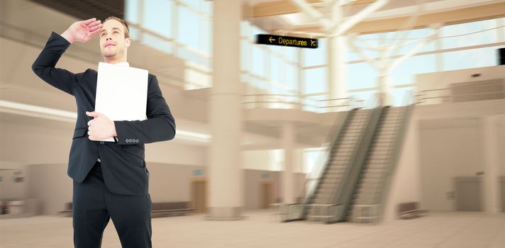 Smiling businessman looking and holding laptop against airport terminal