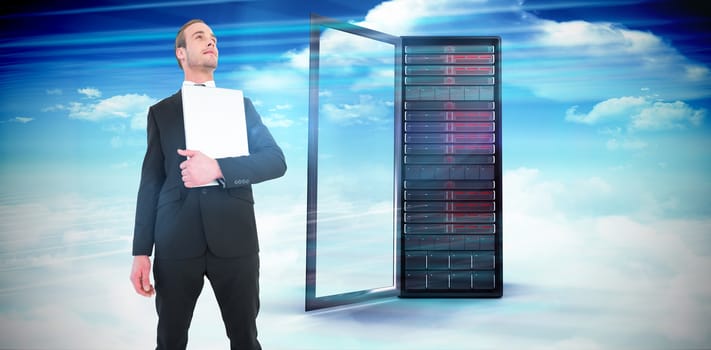 Businessman looking up holding laptop against composite image of server tower