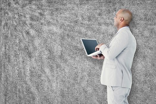 Businessman using laptop against grey background