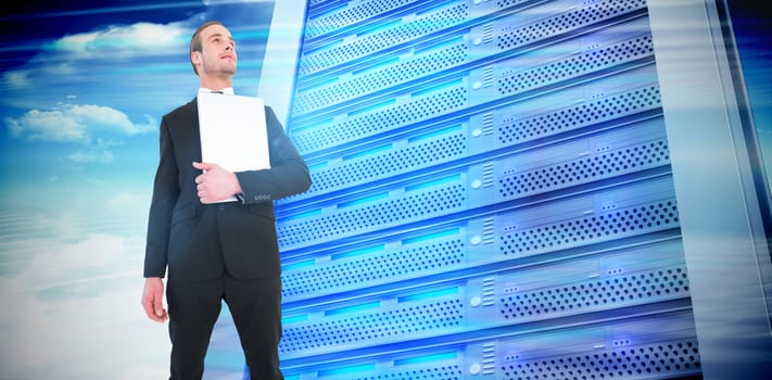Businessman looking up holding laptop against composite image of server tower