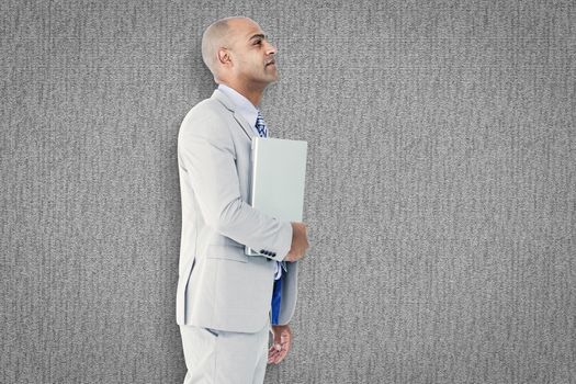 Businessman holding laptop against grey background