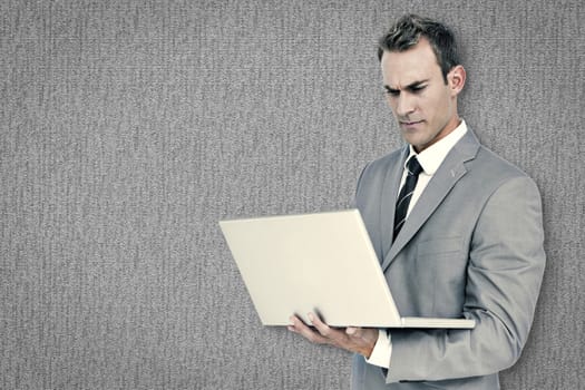 Businessman using laptop against grey background