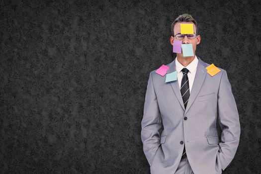 Businessman with post its on face against grey background