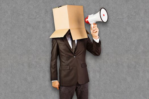 Anonymous businessman holding a megaphone against grey background
