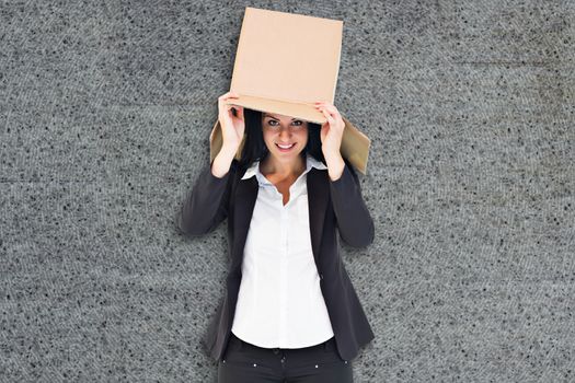 Businesswoman lifting box off head against grey background