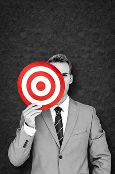 Businessman holding target against grey background