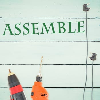 The word assemble against tools on wooden background