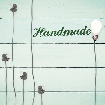 The word handmade against light bulbs on wooden background