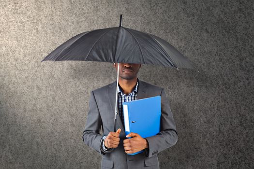 Businessman standing under umbrella against grey background