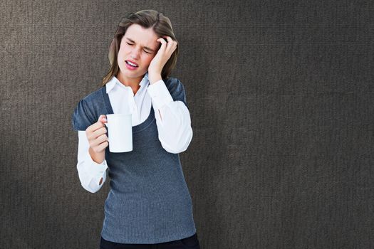 Woman with headache holding mug  against grey background