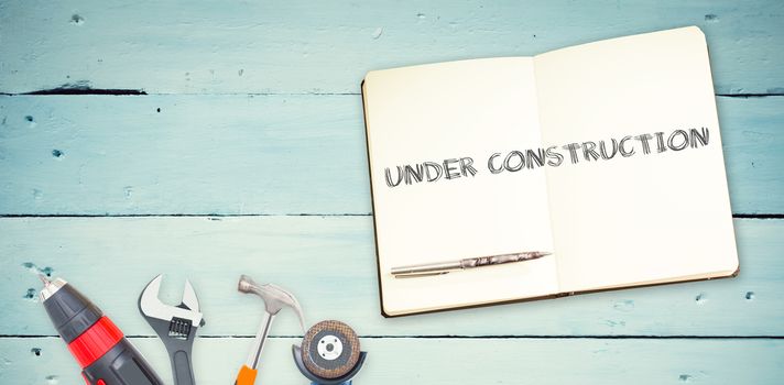 The word under construction against tools and notepad on wooden background