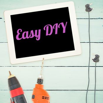 The word easy diy against tools and tablet on wooden background