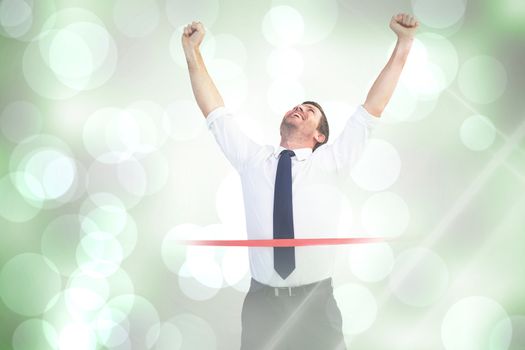 Businessman celebrating success with arms up against grey abstract light spot design