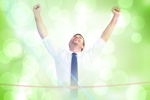 Businessman crossing the finish line against green abstract light spot design