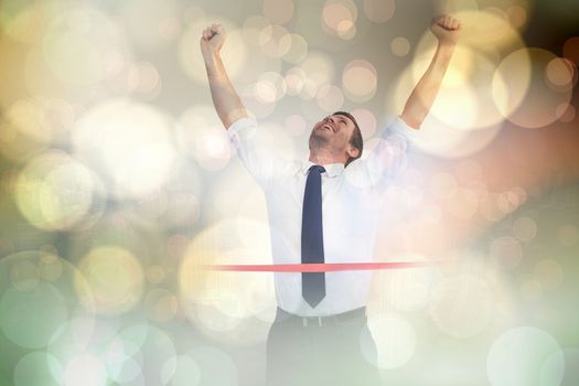 Businessman celebrating success with arms up against yellow abstract light spot design