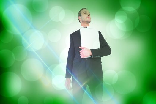 Businessman looking up holding laptop against green abstract light spot design