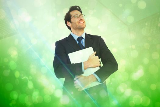 Handsome businessman holding his laptop  against green abstract light spot design