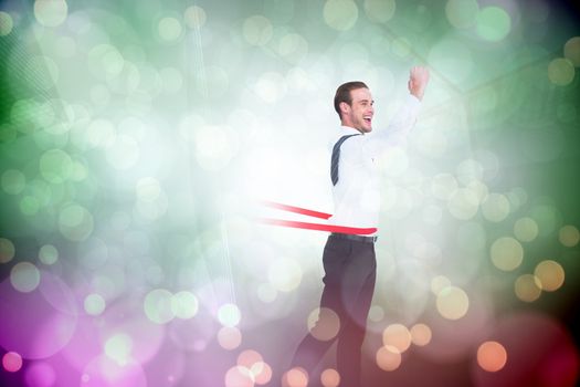 Businessman crossing the finish line against green abstract light spot design